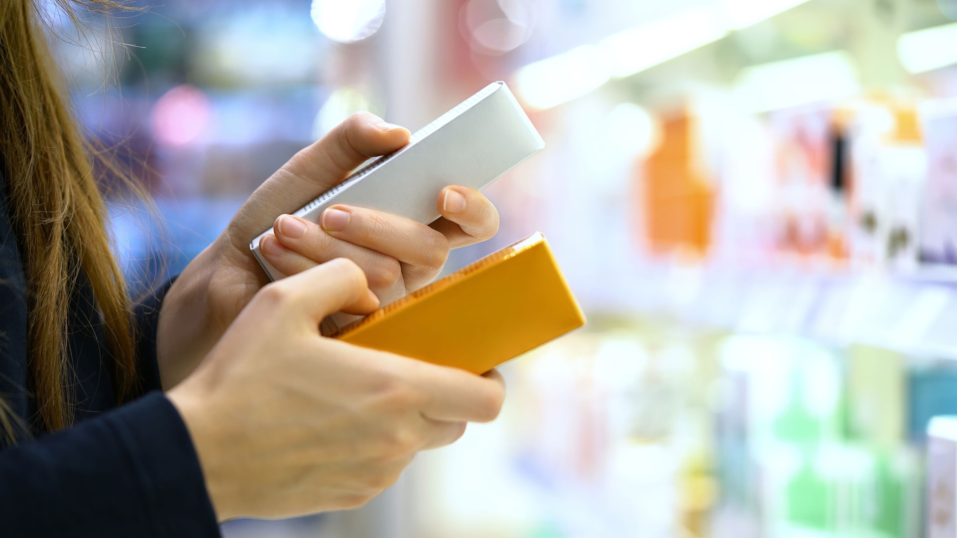 A female customer compares two skincare product, reading labels with ingredients